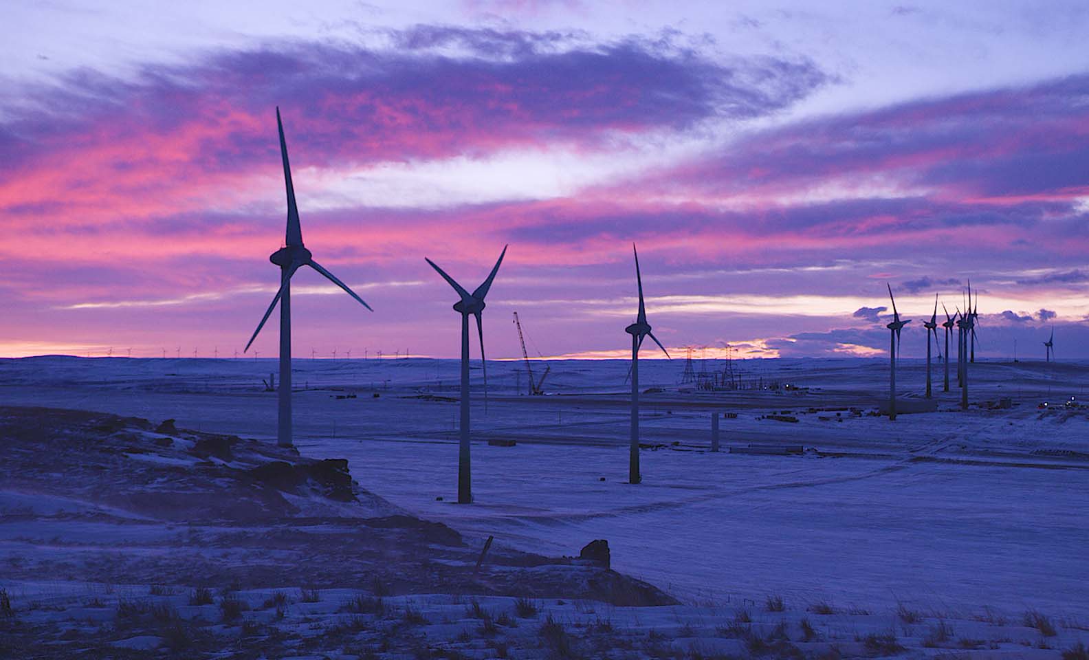 Wind turbines at sunset over snowy landscape
